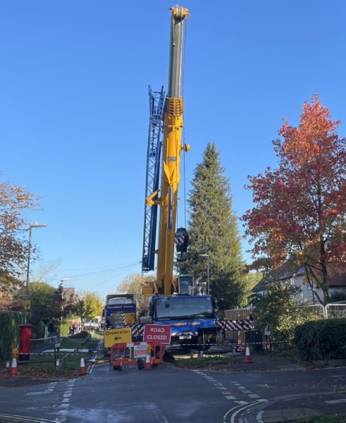 A very large crane prepares to lift the first modular home into place.