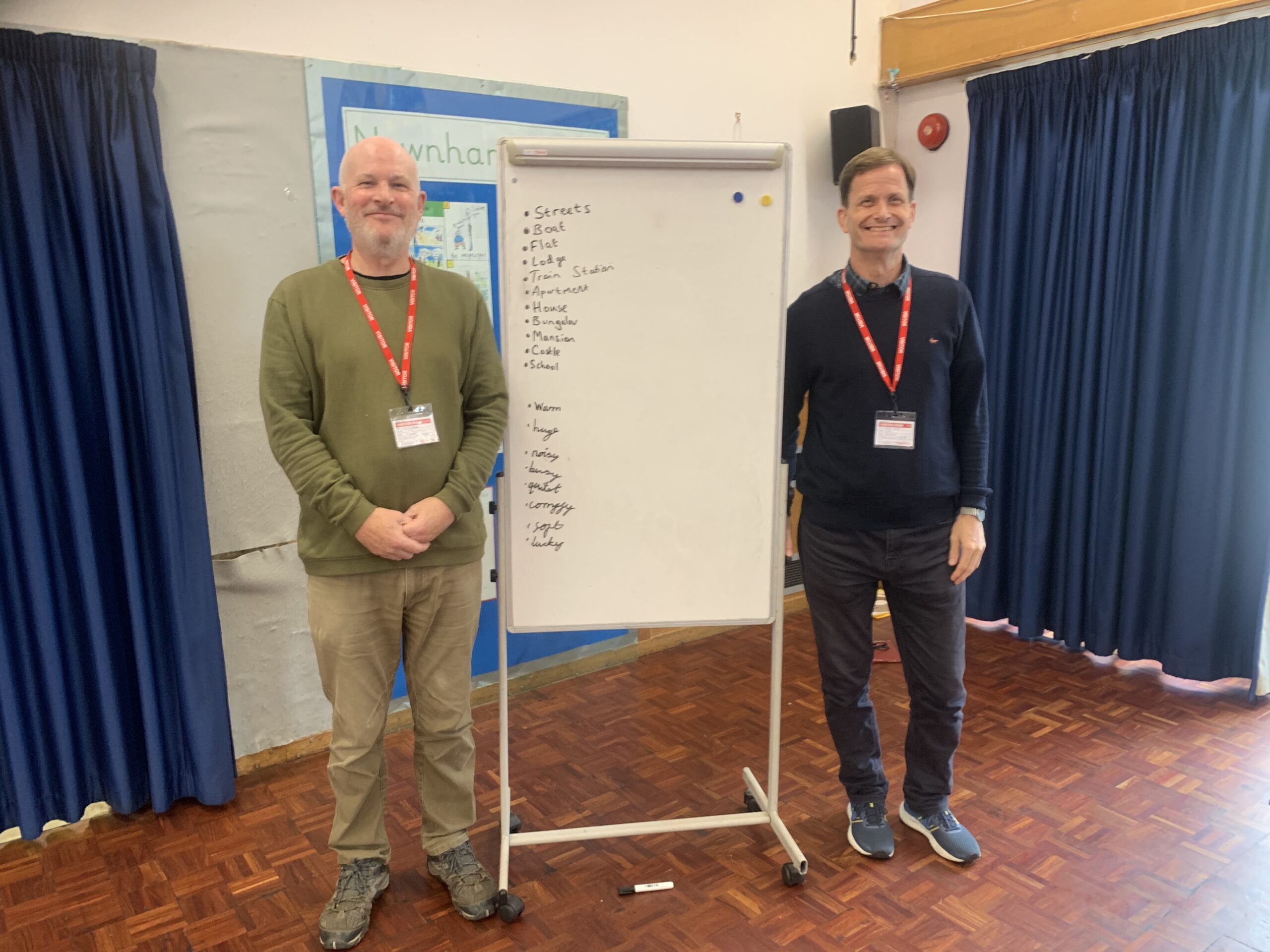 Barry and Matt from ITAC smile at the camera standing either side of a Flipchart in a school assembly hall