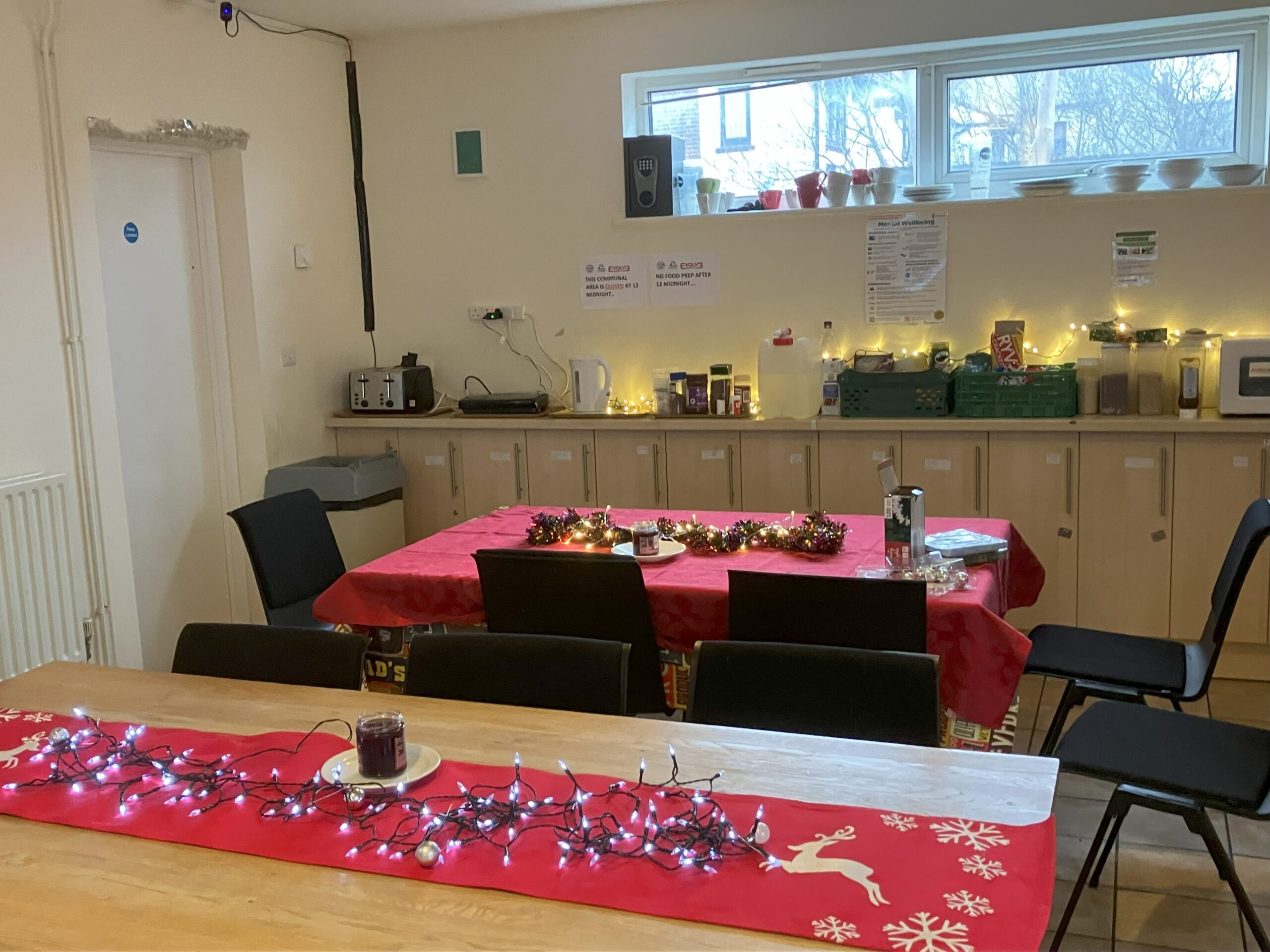 Two long dining tables decorated for Christmas dinner with lights and crackers