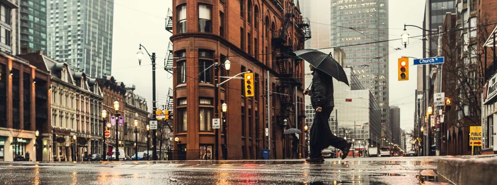 A wet city street with buildings reflected in a puddle in the foreground