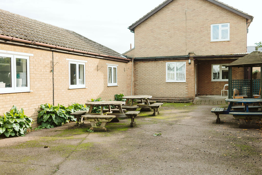 View of the garden at Crossways looking towards the Annex. There are three garden tables and the pergola is in the right hand corner of the photo