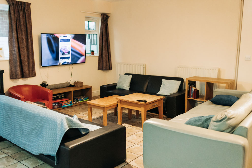 View of three sofas, coffee table and large, wall mounted TV in the Crossways lounge