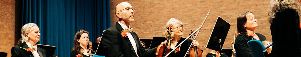 Violinists listen to Matt Addressing audience at concert