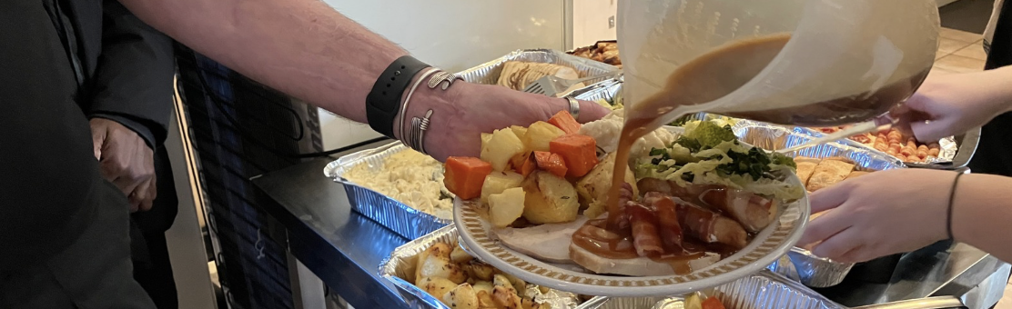 A plate of Christmas dinner with gravy being poured from a large jug