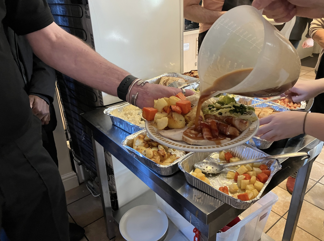 A plate of Christmas dinner with gravy being poured from a large jug