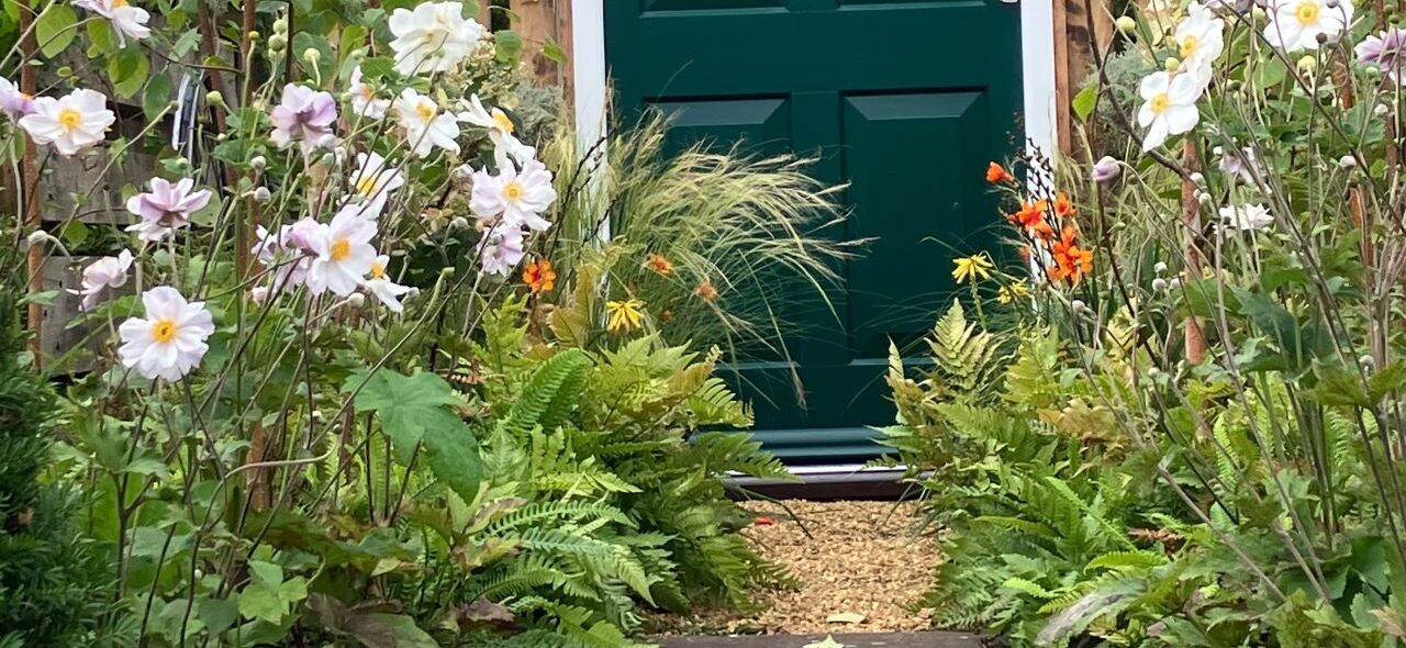Garden Door Photo looking up the path of the beautiful border towards a green front door