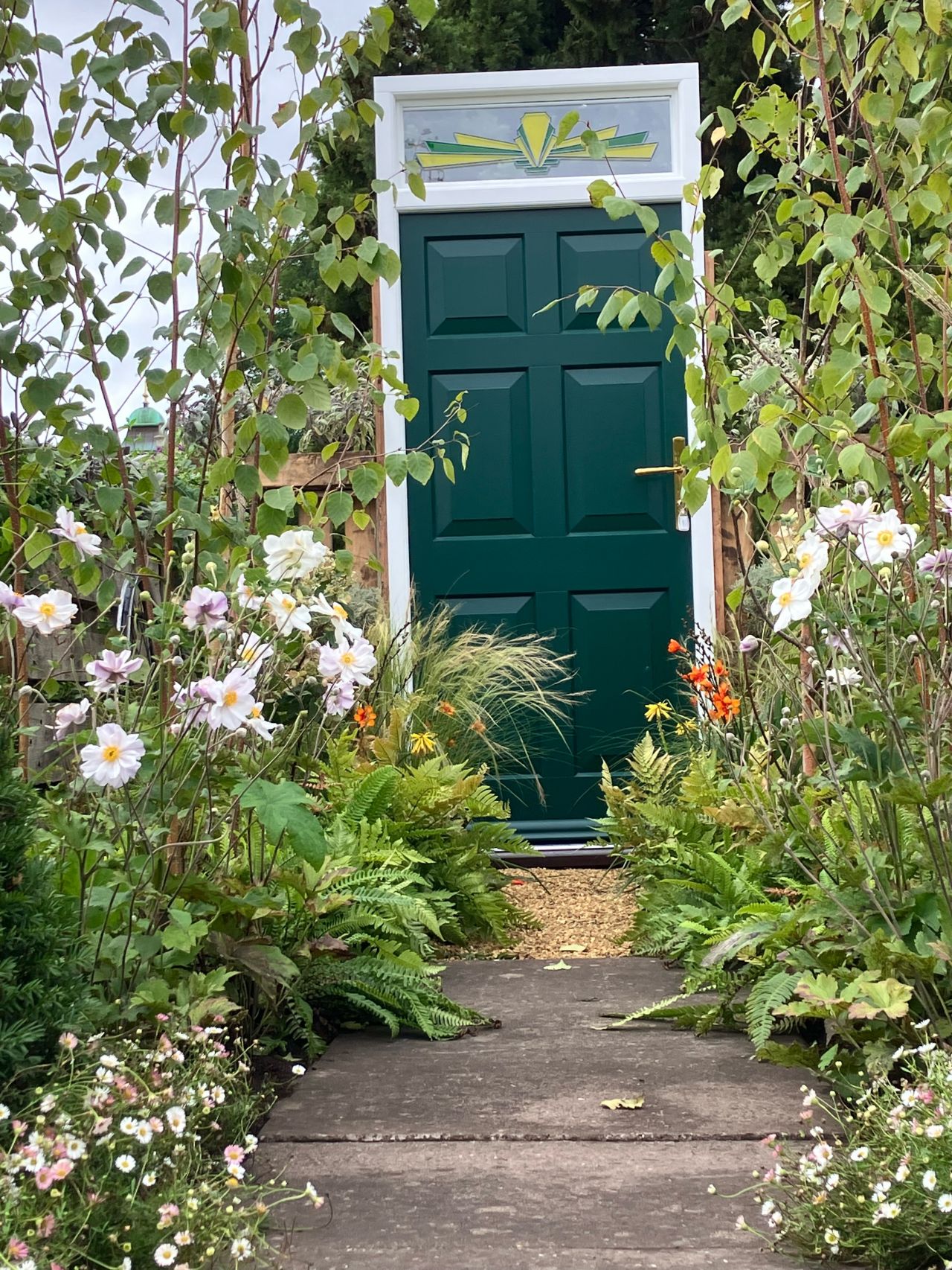 Photo looking up the path of the beautiful border towards a green front door